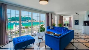 A spacious living room with a large window offering a view of a coastal city. - Crown of La Concha Beach by DonosRent (San Sebastián)