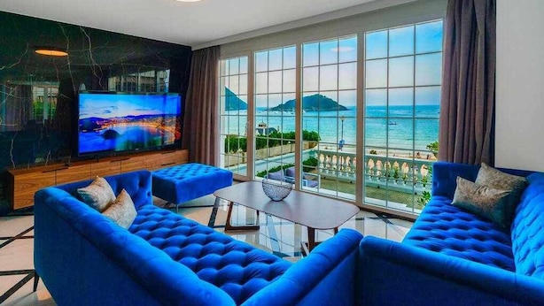 A living room with a large TV, blue sofas, a coffee table, and a view of the sea. - Crown of La Concha Beach by DonosRent (San Sebastián)