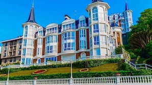 A large, multi-story building with a classic architectural style, featuring prominent towers and bay windows. - Crown of La Concha Beach by DonosRent (San Sebastián)