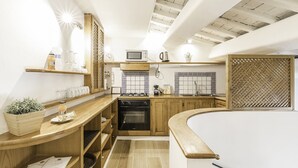 A compact kitchen with wooden cabinets, a microwave, and a stove. - Thebestinrome Luxury Orbitelli (Roma)