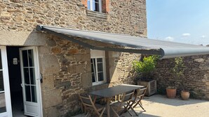 A stone building with a covered patio, a table, and chairs. - Country house Near Dinard and Saint Malo (Pleurtuit)
