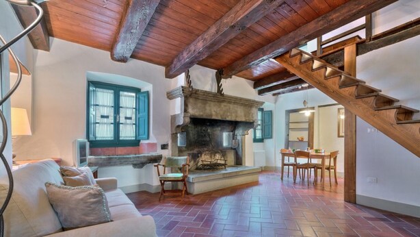 A cozy living room with a fireplace, wooden staircase, and a dining area. - CASTLE OF SARNA Casa Cisterna  (Sarna, Chiusi della Verna)