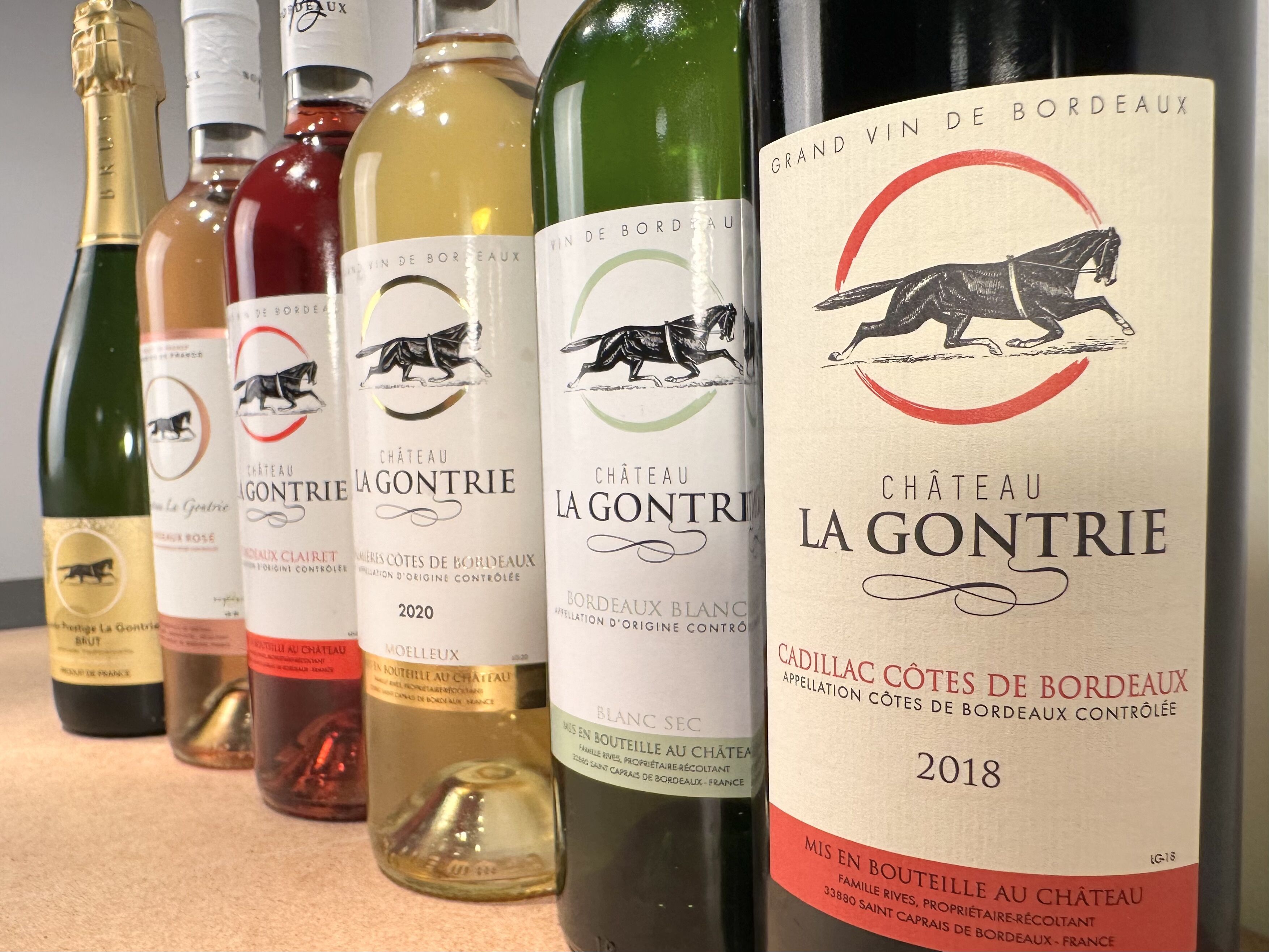 Una hilera de botellas de vino con etiquetas que indican que son del Chateau La Gontrie, incluyendo una botella del 2020 y una del 2018.