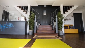 A reception area with a staircase, reception desk, and potted plants. - Villa Caparica Hostel (Almada)