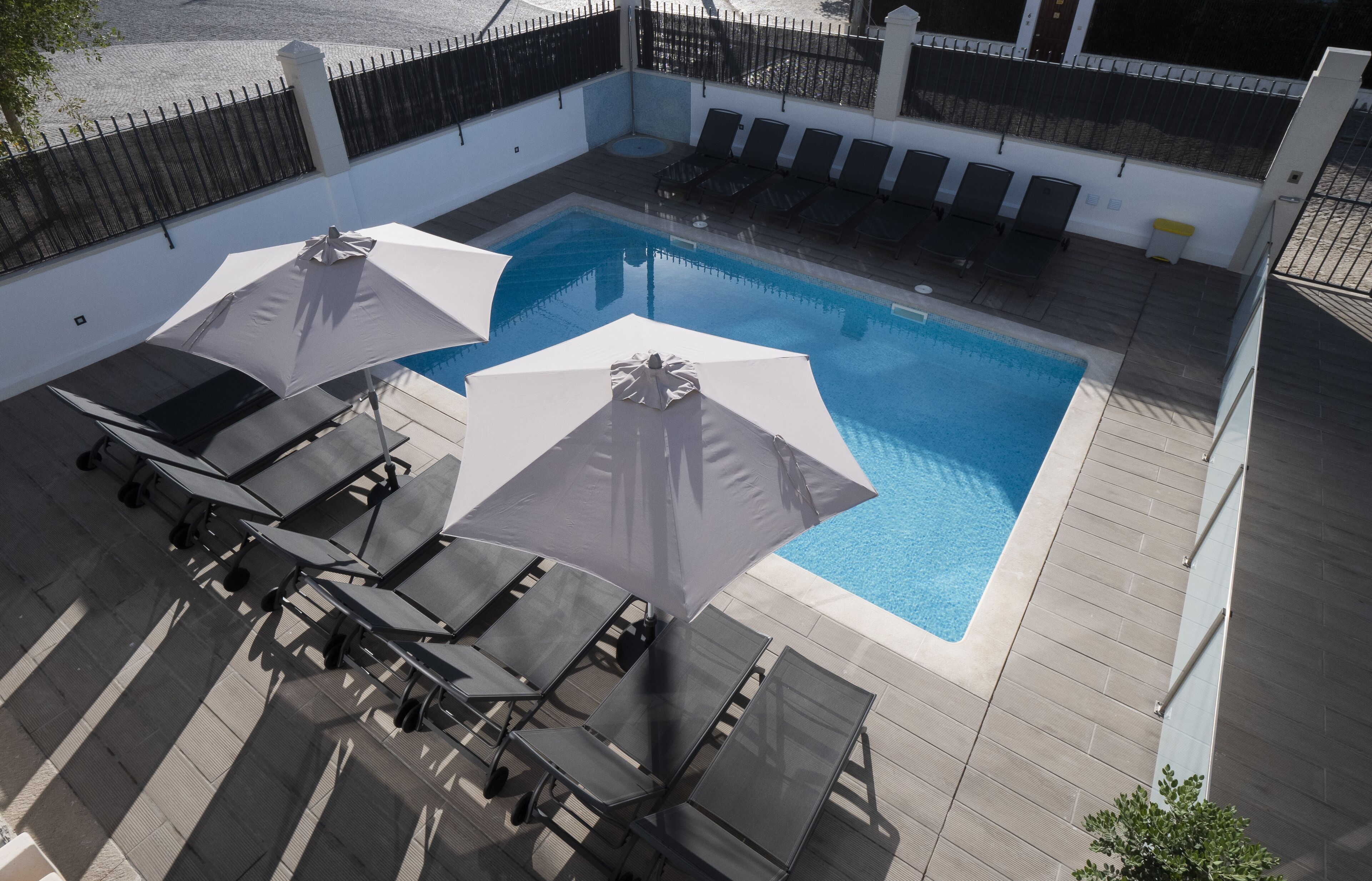 Zona de piscina en la azotea con sillones de descanso y sombrillas.