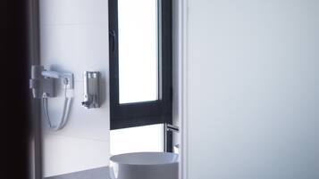 Ein modernes Badezimmer mit einem weißen Waschbecken, einem Spiegel und einem Handtuchhalter.