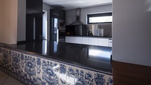 A modern kitchen with a black countertop, white cabinets, and a window above the sink. - Villa Caparica Hostel (Almada)