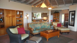 A spacious living area with a high ceiling, wicker furniture, and a view into the kitchen. - Spacious, 3 Bed / 3 Bath, Pool, Screened Porch, Wi-Fi, A/C (Cruz Bay, St.John)