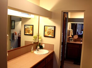 Une salle de bain avec un grand miroir, un lavabo et un tableau encadré accroché au mur.