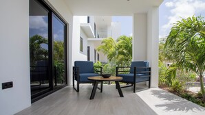 A modern outdoor seating area with two blue chairs and a round table, surrounded by plants and a clear sky. - Sirena Resort Curaçao (Willemstad)