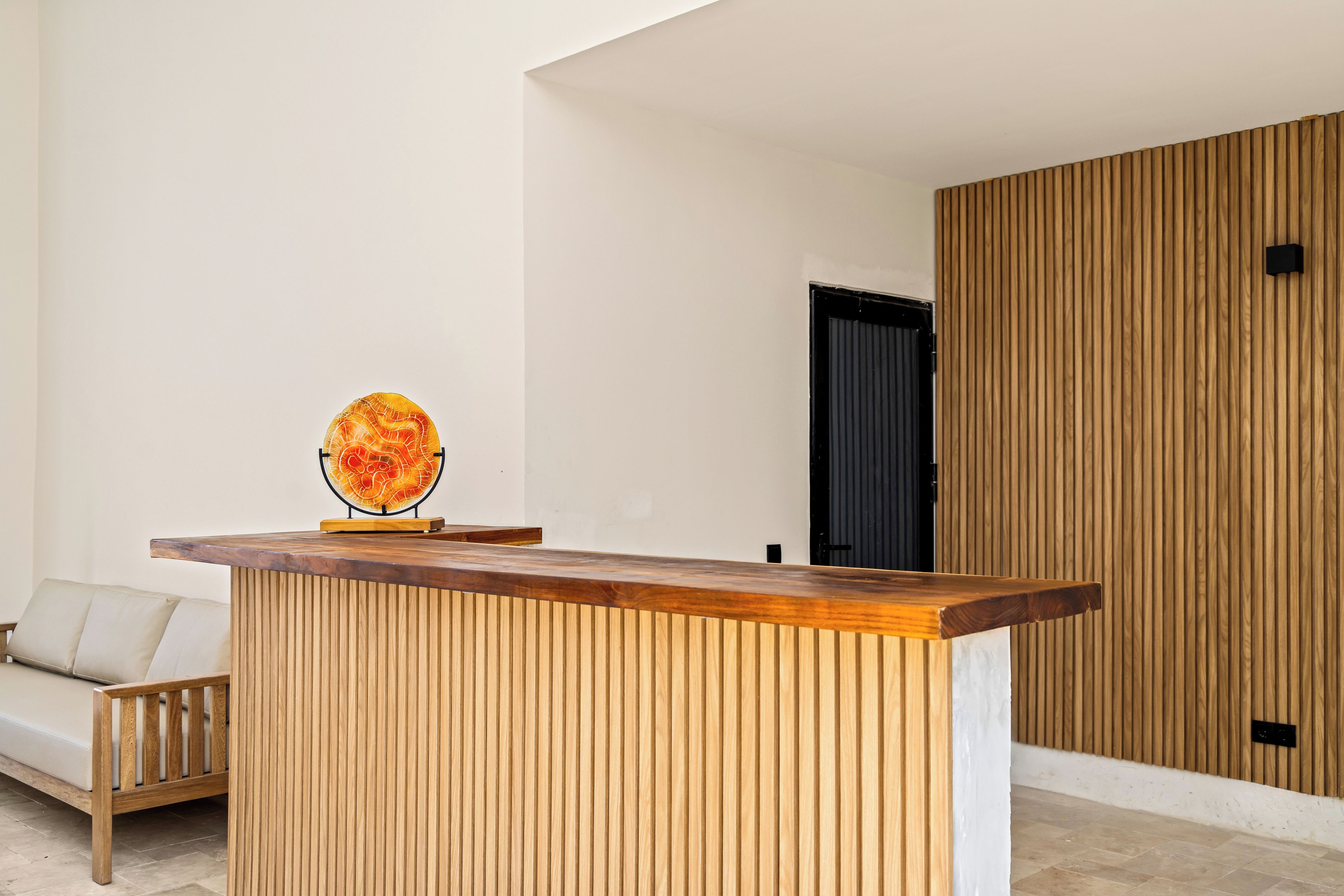 Un intérieur moderne avec un comptoir d’accueil en bois, un canapé et une porte.