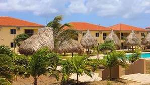 Un resort con diversi edifici, capanne con tetto di paglia e una piscina.