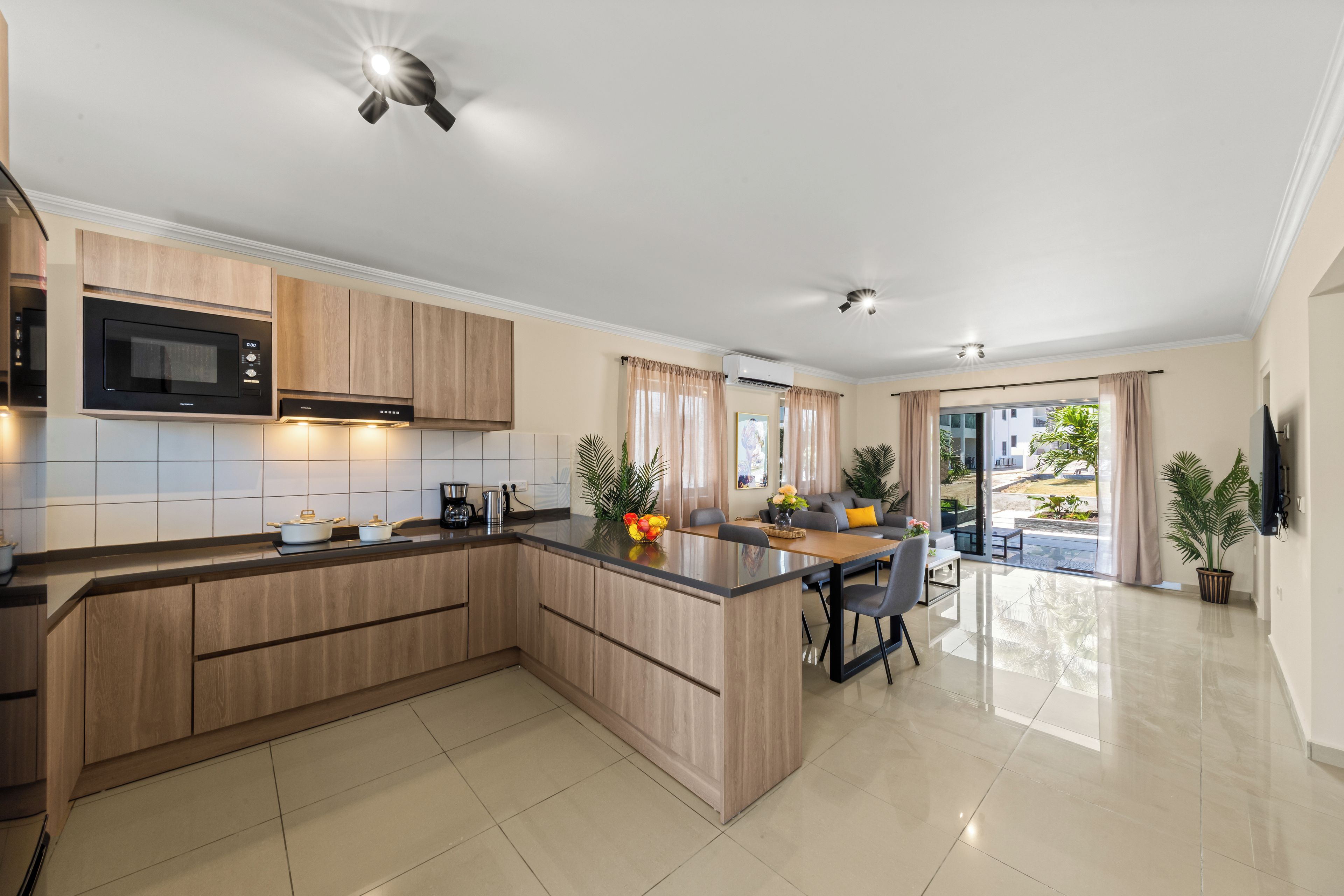 A modern kitchen with a central island, built-in oven, and a dining area with a view.