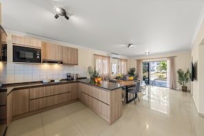 Una cocina moderna con una isla central, horno empotrado y un comedor con vistas.