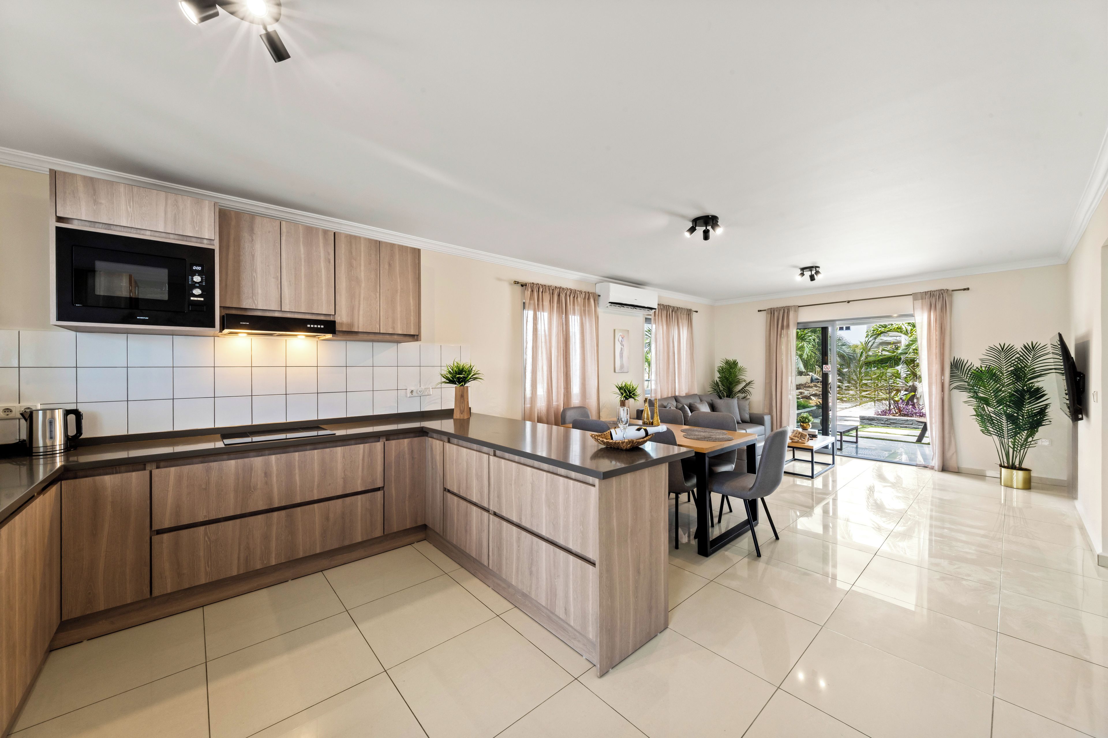 Una cocina moderna con microondas integrado, un comedor con mesa y sillas, y vista al exterior a través de amplios ventanales.