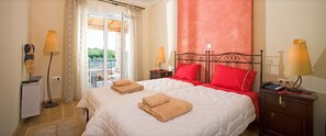 Une chambre d’hôtel comprenant un lit, deux lampes de chevet, une table de chevet, un bureau avec une lampe et une vue sur l’extérieur grâce à une porte vitrée.