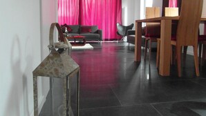 A modern living room with a dark floor, a wooden dining table, a sofa, and a chair.