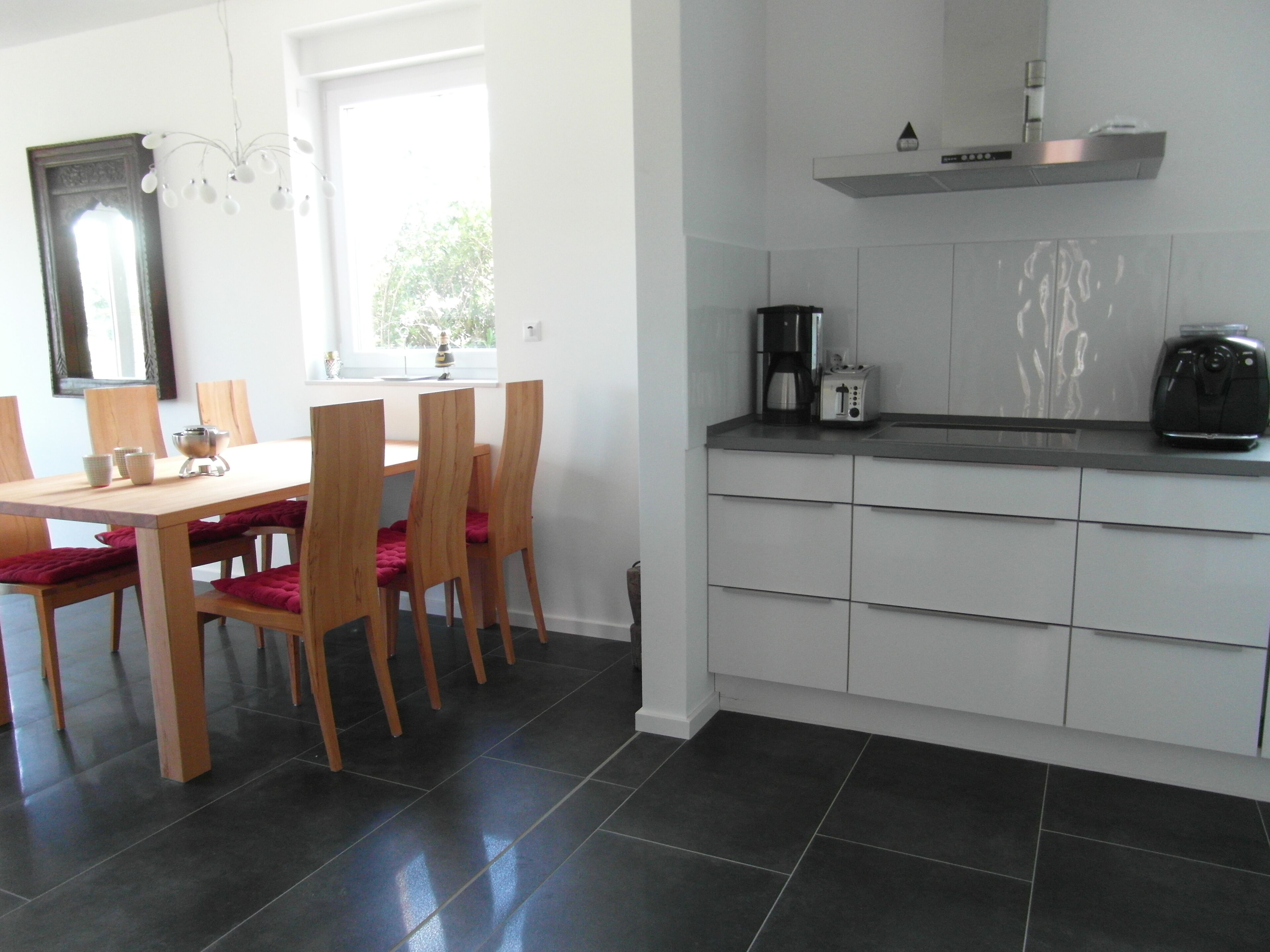 A modern kitchen with a dining area. It includes a kitchen counter, a coffee maker, and a dining table with chairs.