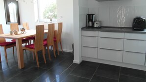 A modern kitchen with a dining area. It includes a kitchen counter, a coffee maker, and a dining table with chairs.