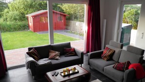A modern living room with two sofas, a coffee table, and a view of a red shed in the backyard.