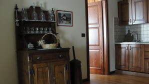 Un armadietto in legno con vetreria e un cesto, una porta in legno e uno schienale piastrellato in una cucina.