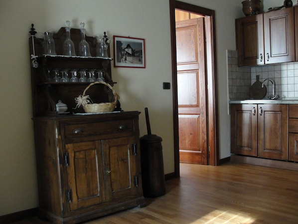 Un meuble en bois contenant de la verrerie et un panier, une porte en bois et un pare-feu en carreaux dans une cuisine.