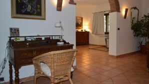 Une pièce avec un bureau en bois, une chaise en osier et un tableau encadré accroché au mur.