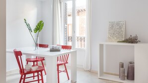 Ein weißer Esstisch mit roten Stühlen, eine Vase mit grünen Blättern und eine Karte an der Wand.