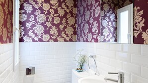 Ein Badezimmer mit weiß gefliesten Wänden, einem weißen Waschbecken und einer Toilette.
