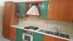 Una cocina con gabinetes de madera, un lavamanos de acero inoxidable y un horno empotrado.