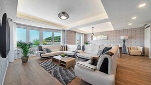 A spacious living room with a sectional sofa, a coffee table, and a large window offering a view of the outdoors.