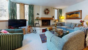 Un salon chaleureux avec une cheminée, un téléviseur et des fauteuils confortables.
