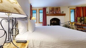 Une chambre à coucher avec un lit, une lampe, une cheminée et une fenêtre avec des rideaux.