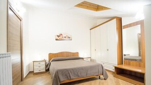 Een slaapkamer met een houten bed, nachtkastje, een kaptafel en een grote spiegel.