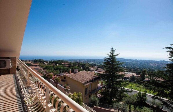 A balcony with a view of a residential area, including houses and trees.