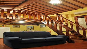 Ein Zimmer mit einer Holztreppe, einem Sofa und einer Küchenzeile.