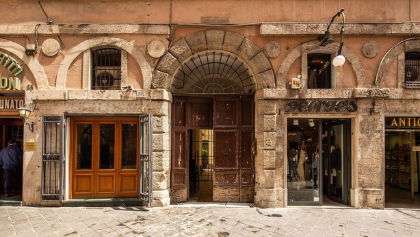A historic building with arched doorways and a cobblestone street.