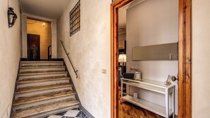 A staircase with a checkered floor leading to a room with a white console table and a mirror.