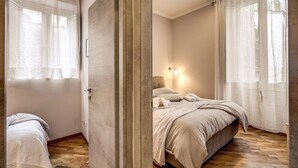 A bedroom with a bed, a nightstand, a lamp, and a door.