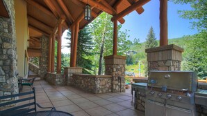 An outdoor patio with stone walls, wooden beams, and a built-in grill station.