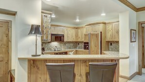 A kitchen with wooden cabinets, a central island with bar stools, and built-in appliances.