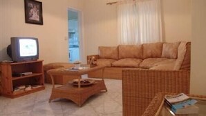 A living room with a sofa, a television, a coffee table, and a wicker chair.
