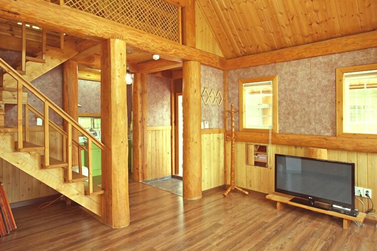 Ein geräumiges Zimmer mit einer Holztreppe, einem Flachbildfernseher und einem großen Fenster.
