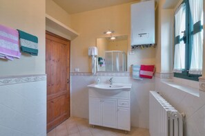 A bathroom with a white sink, a mirror, a towel rack, a shower, and a radiator. - Sarna Castle, Portico (Sarna, Chiusi della Verna)
