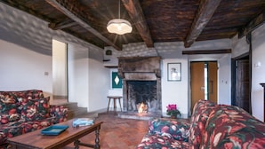 A cozy living room with a fireplace, floral sofas, and a wooden ceiling. - Sarna Castle, Portico (Sarna, Chiusi della Verna)
