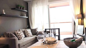 A dining area with a table set for four, a sofa with patterned cushions, and a window with curtains. - Incredible apartment-central-sea view-near the beach-Free Wifi. (Barcelona)