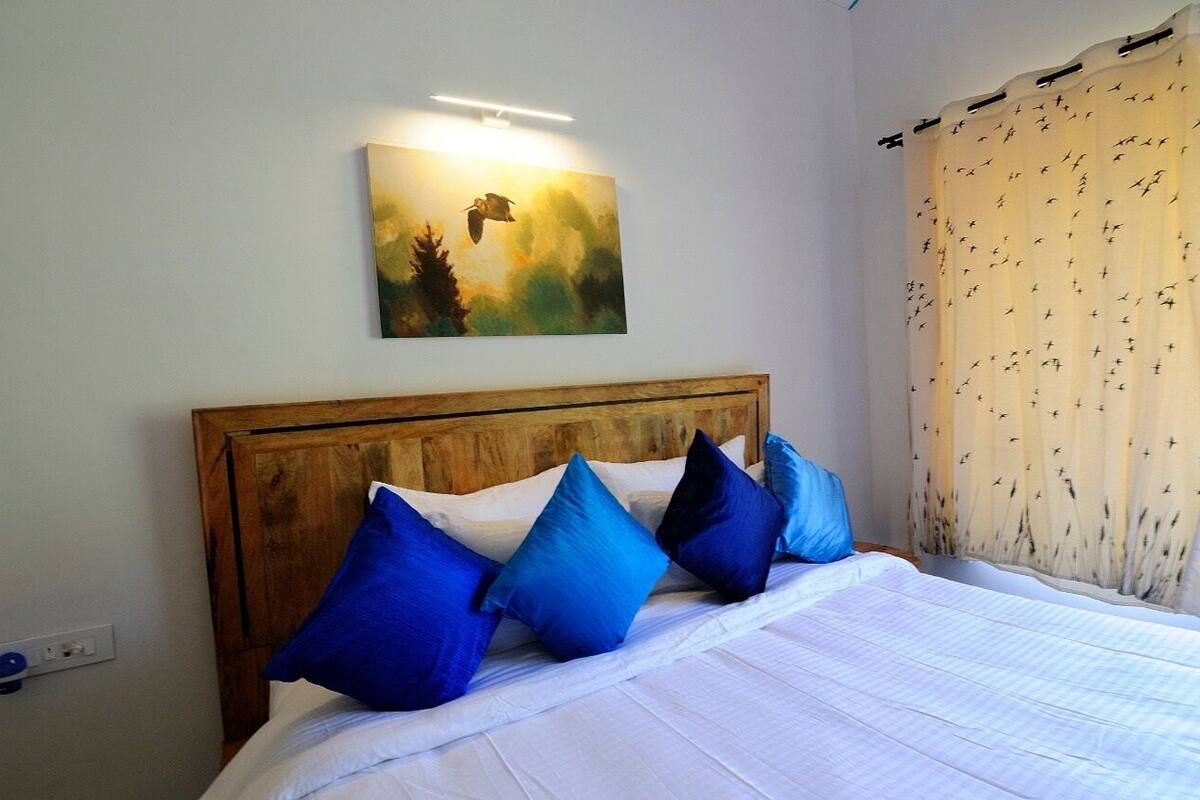 A bedroom with a wooden headboard, white bedding, and blue pillows.