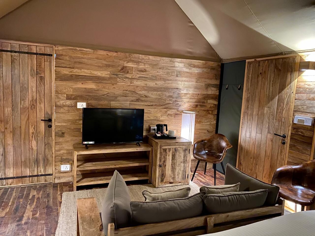 Una sala de estar acogedora con pared de madera, un televisor de pantalla plana, una mesa de centro, un sofá y una silla.