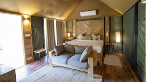 Un dormitorio con piso de madera, una cama, un sofá y un ventilador de techo.