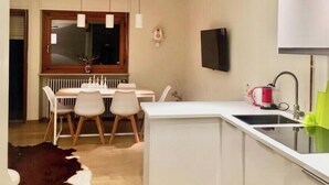 A modern kitchen with a dining area, a TV mounted on the wall, and a radiator under the window. - Brand new apartment with amazing view and close to everything (Sestriere)